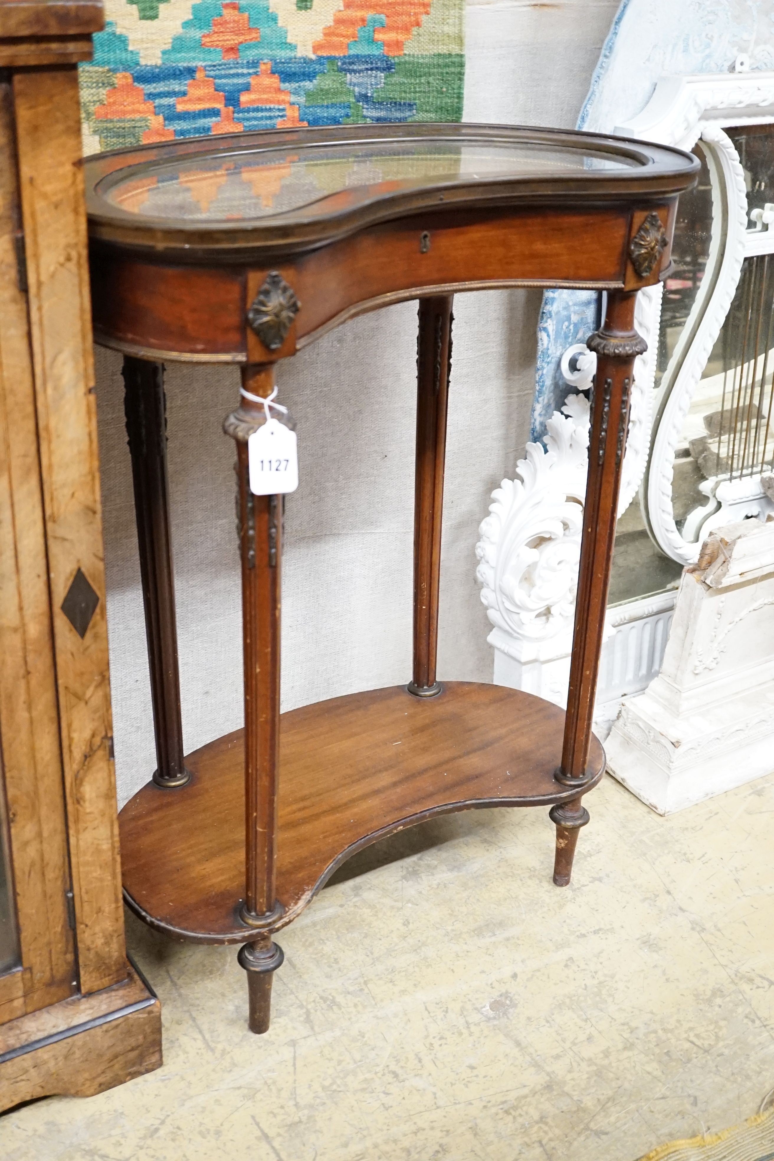 A French two-tier kidney shaped brass mounted mahogany display table, width 62cm, height 80cm